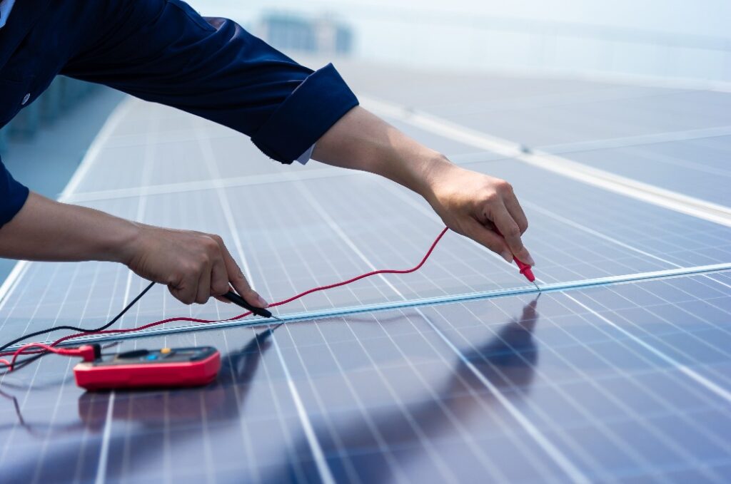 Nahaufnahme: Die Hände der Ingenieure bedienen elektrische Messgeräte auf dem Solarzellenplan.